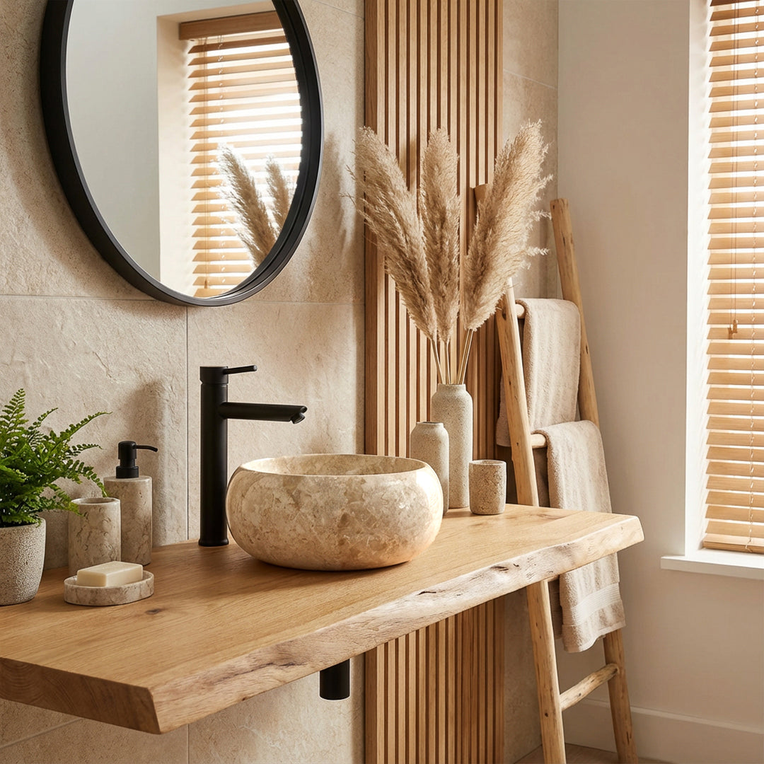 Rundes Aufsatzwaschbecken aus hellem Naturstein auf Holzwaschtisch mit schwarzer Armatur im hellen, modernen Badambiente