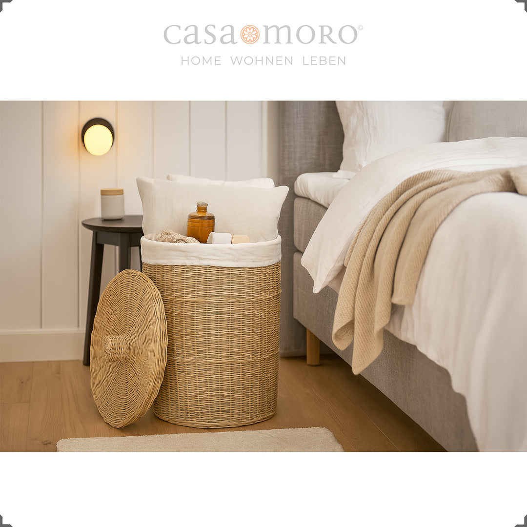 Runder Rattan Wäschekorb mit Deckel im Schlafzimmer, gefüllt mit Kissen, Decken und Pflegeartikeln